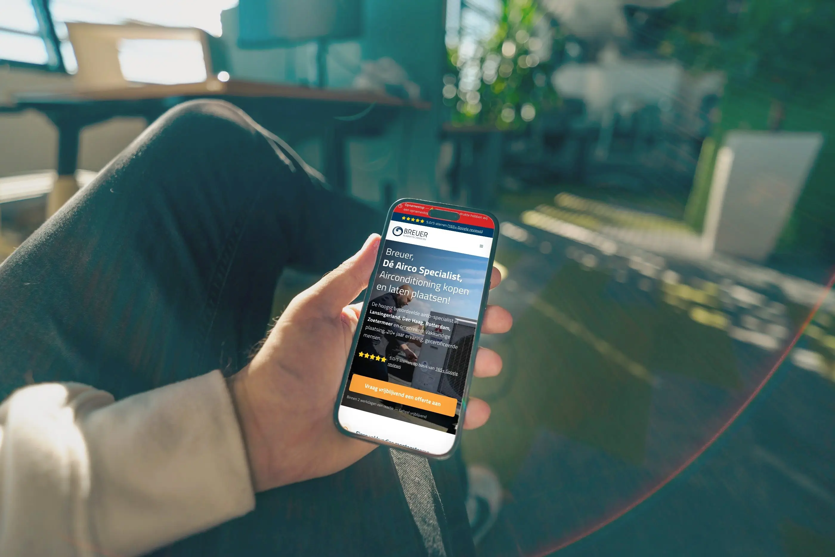 De website van Breuer Klimaattechniek op het scherm van een telefoon in iemands hand.