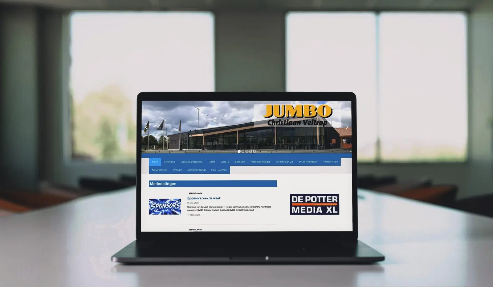 Een laptop op een tafel met de website van een voetbalclub op het scherm.