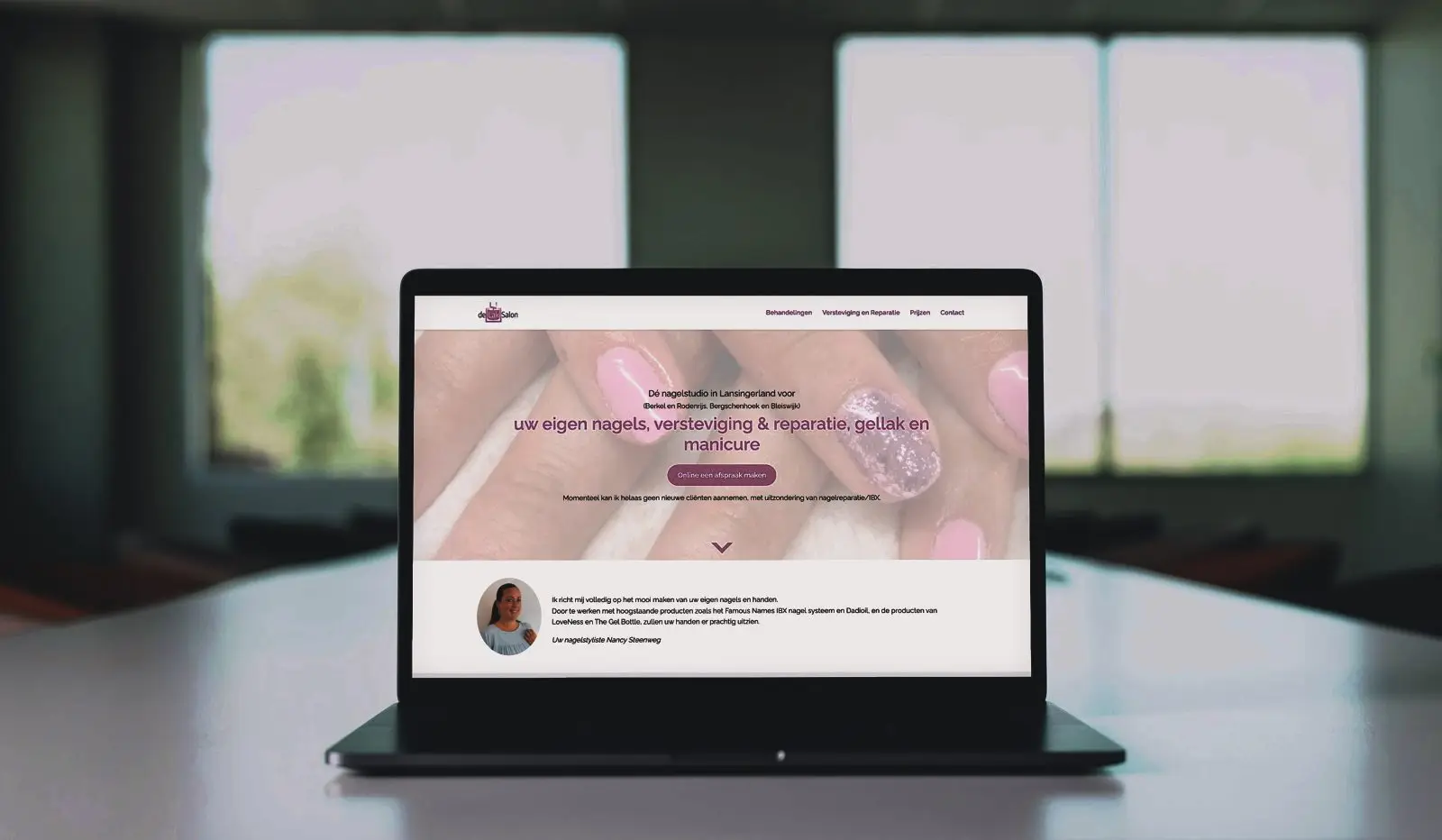 Een laptop op een tafel met de website van een nagelstudio op het scherm.